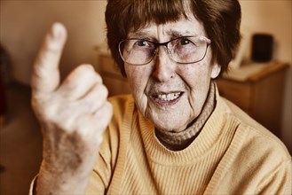Angry senior citizen threatens with her raised index finger