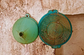 Funnel and sieve bowl made of green plastic hang on the wall