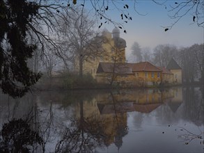 Schloss-Holte moated castle in autumn as fog rolls in