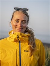 Young woman with rain jacket looks into the camera