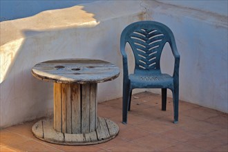 Plastic chair and wooden cable drum as table