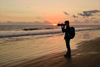 Photographer taking pictures at sunset by the sea