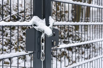 Snow-covered fence with security lock