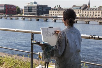 Painter with easel sketches the Oberbaum Bridge in Treptow