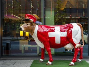 Cow figure with the symbol of the Swiss flag in front of the Moevenpick Hotel