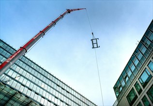 Lifting crane replacing a glass pane on an office building