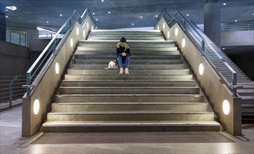 Teenager sitting alone on the steps of an underground station