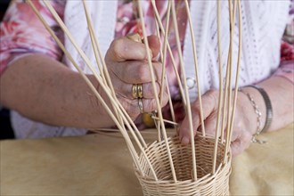 Hands of an 86-year-old senior citizen in a nursing home weaving a basket