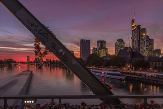 View through a bridge railing with love locks onto the Main River and the high-rise buildings of Frankfurt am Main