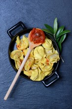Pasta in pot and cooking spoon with tomato sauce