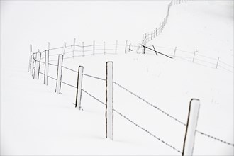 Snow-covered pasture fence in wintry landscape
