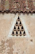 Entry triangle under the roof for pigeons in house wall
