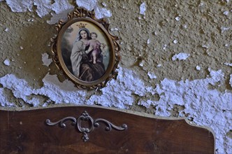 Image of the Virgin Mary over bed on wall with peeling paint