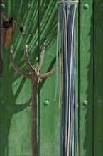 Wooden pitchfork leaning against green wooden door
