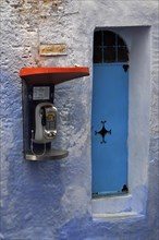 Modern public telephone next to blue door