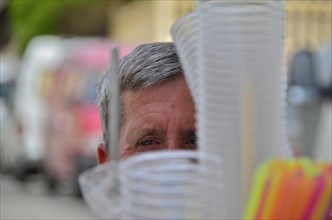 Man looking out from behind plastic cup