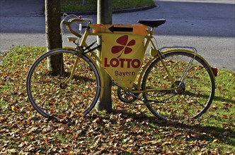 Yellow bicycle in autumn leaves advertises lottery shop