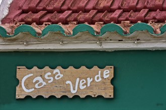 Wooden sign on green wall by Casa Verde