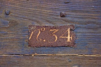 Rusty house number 34 on wooden wall
