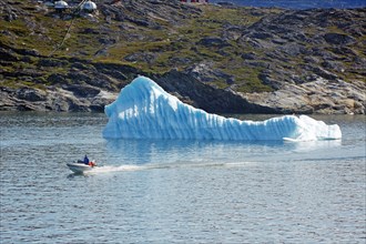 Small boat in front of iceberg near Ilulisaat harbour