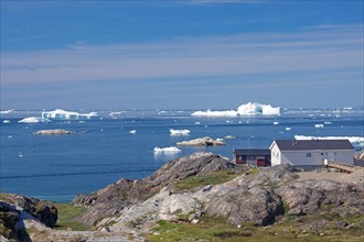 Simple dwellings on the edge of an iceberg-covered bay