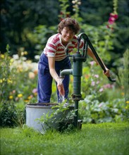Woman pumps water in the garden