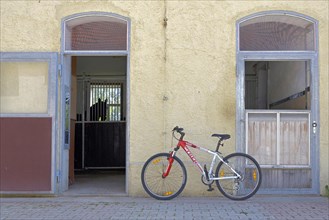 Bicycle leaning against wall in front of horse stable