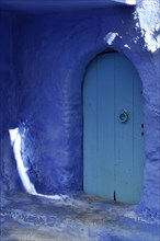Blue wooden door in round arch with blue wall