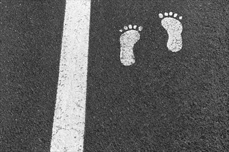 White line and two footprints on asphalt