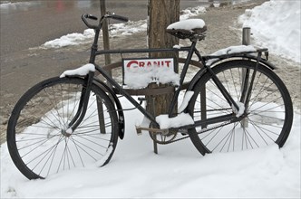Black bicycle in the snow advertises Granit workshop