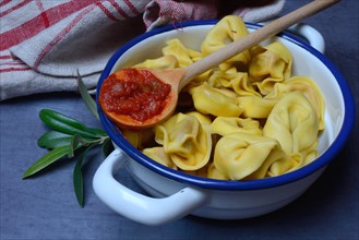 Pasta in pot and cooking spoon with tomato sauce