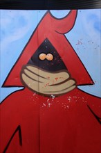 Red figure with hood and mouth guard sprayed on metal door