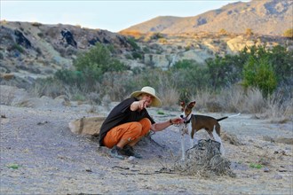 Woman with straw hat squatting talking to her dog