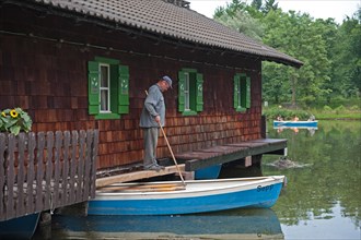 Wooden house with man on jetty at boat rental Hinterbruehler See