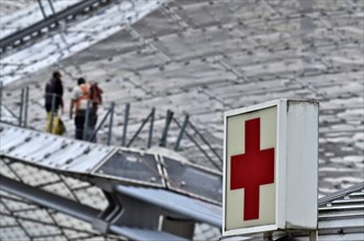 Worker on roof of Olympic tent with Red Cross sign