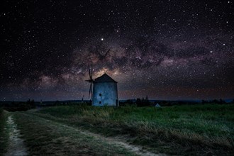 The Old Windmill of Tes iin the night with Milky Way and starry sky. Windmill made of stone and wooden wings in Tez