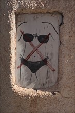 Wooden sign with bikini forbidden on wall of restaurant