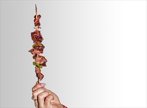 A hand holding a roast beef skewer
