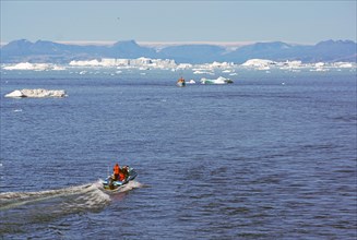 Small boat in front of iceberg near Ilulisaat harbour