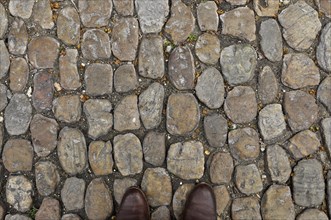 Brown shoe tips on brown stone pavement