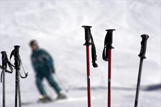 Ski poles stuck in snow with skier