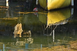 Bow of ship with buoy reflected on greenish water