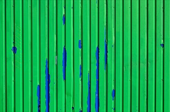 Bright green wall with blue paint residue on metal container