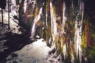 The Burgbach waterfall with snow in winter. Waterfall with stone steps in Schapbach