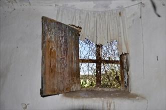 Window with broken plastic curtain in abandoned house