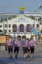 Group of men in traditional traditional costume with lederhosen in front of Hofbraeu tent