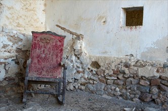 Stained rocking chair in front of old wall in abandoned house