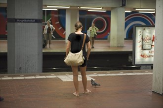 Young woman with pigeon waiting at track in underground station