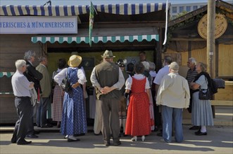 Group of people in traditional traditional costume in front of stand with Bavarian