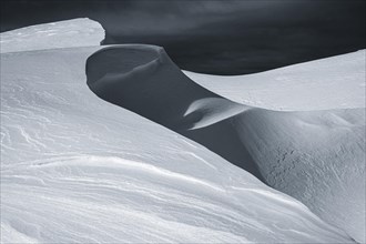 Snow cornice against a dark sky at the summit of Toreck